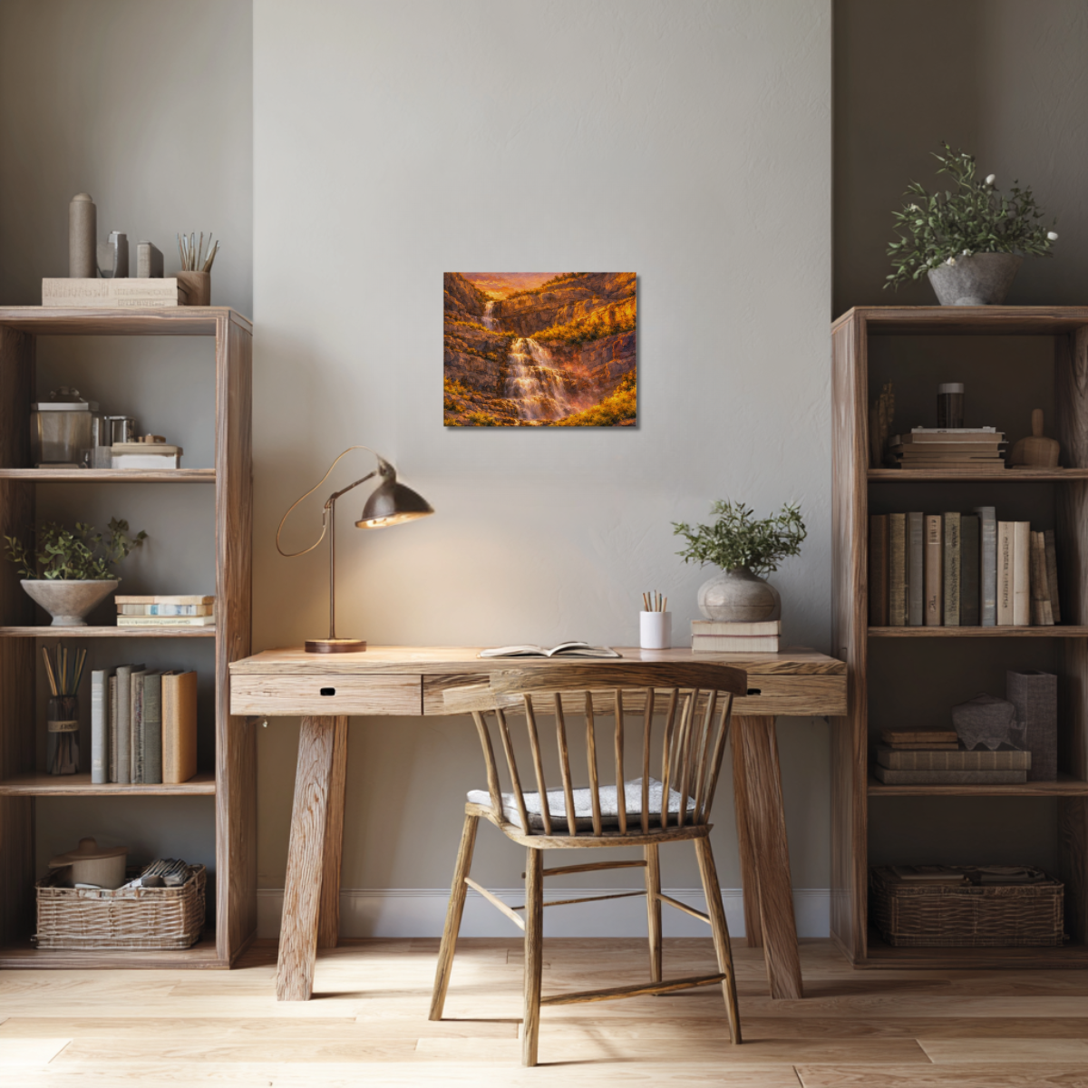 Home office with wooden desk, chair, bookshelves, and canvas wall art of Bridal Veil Falls at sunset.