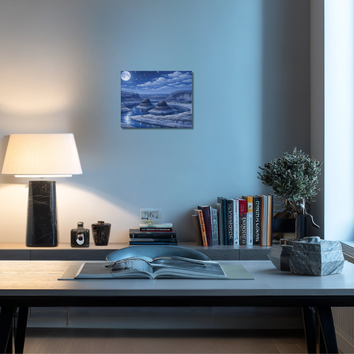 Modern office desk with lamp, books, and decorative items against a light blue wall with canvas wall art depicting Reflection Canyon Utah at night.