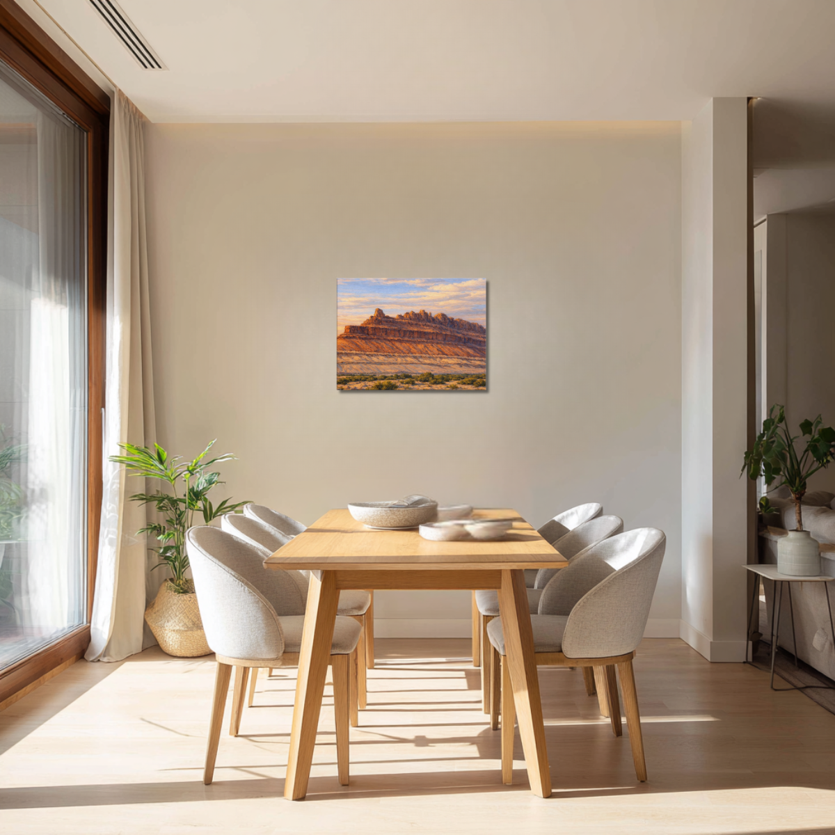 Dining room with wooden table and chairs, large window, and wall art canvas print of the Rock Ship formation during sunrise at Black Dragon Canyon.