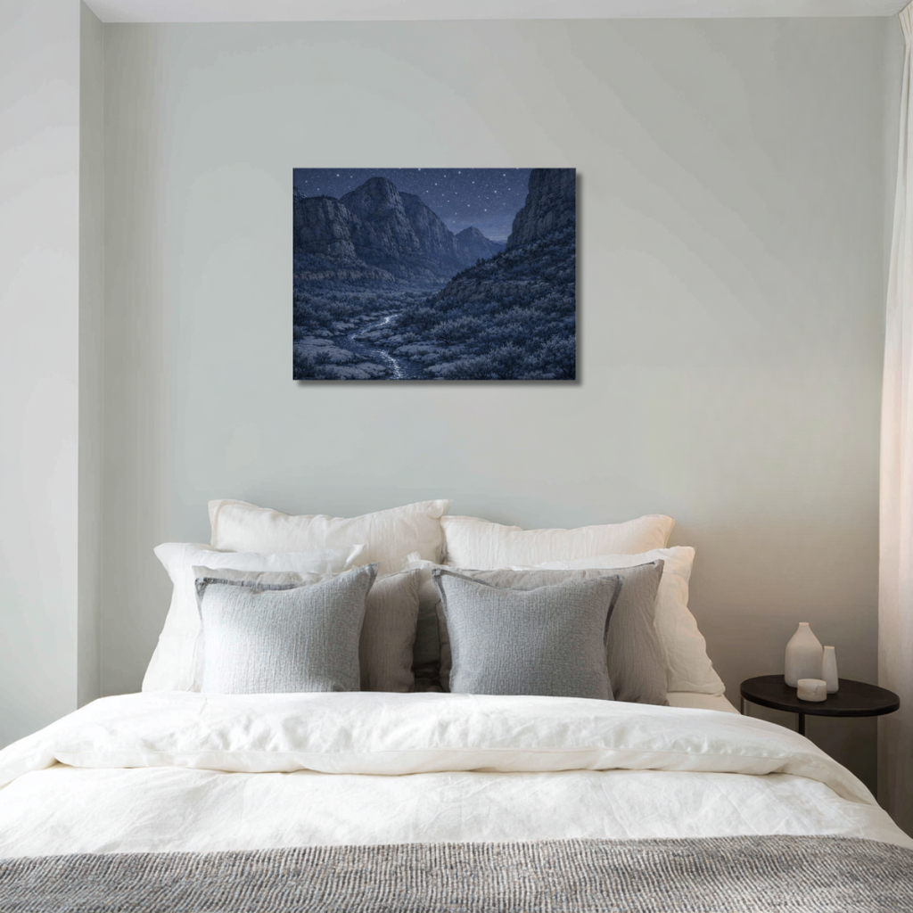Bedroom with a bed featuring white and gray pillows, a nightstand with a lamp, and a wall art piece of Zion's National Park at night landscape.